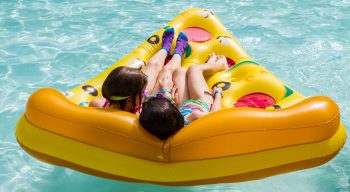 Two girls on pizza floaty in pool