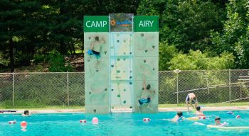 Airy campers climbing rock wall by pool