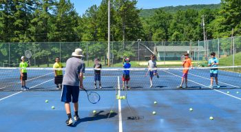 Campers learning how to serve at tennis